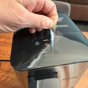 Eine Folie wird vom Display der Philips Water Station abgezogen.