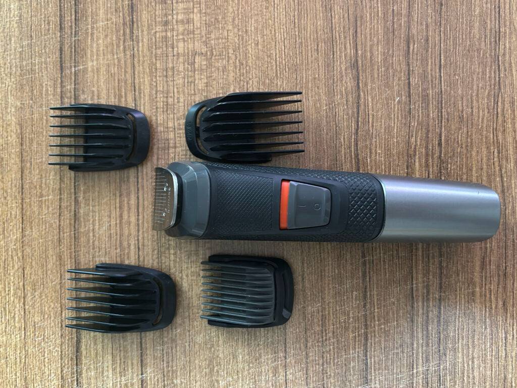 Ein getesteter Haarschneider mit vier verschiedenen Aufsätzen auf einer Holzoberfläche liegend.