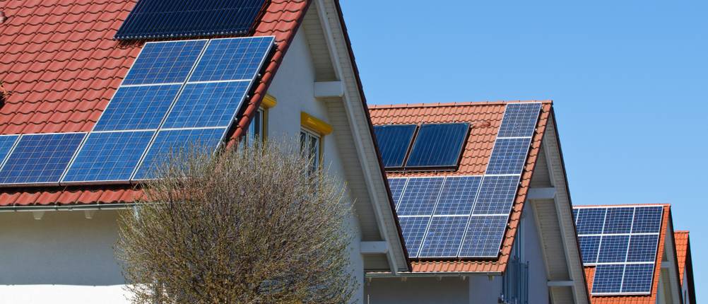 Eine Reihe von Häusern hat verschiedene Photovoltaikmodule auf dem Dach.