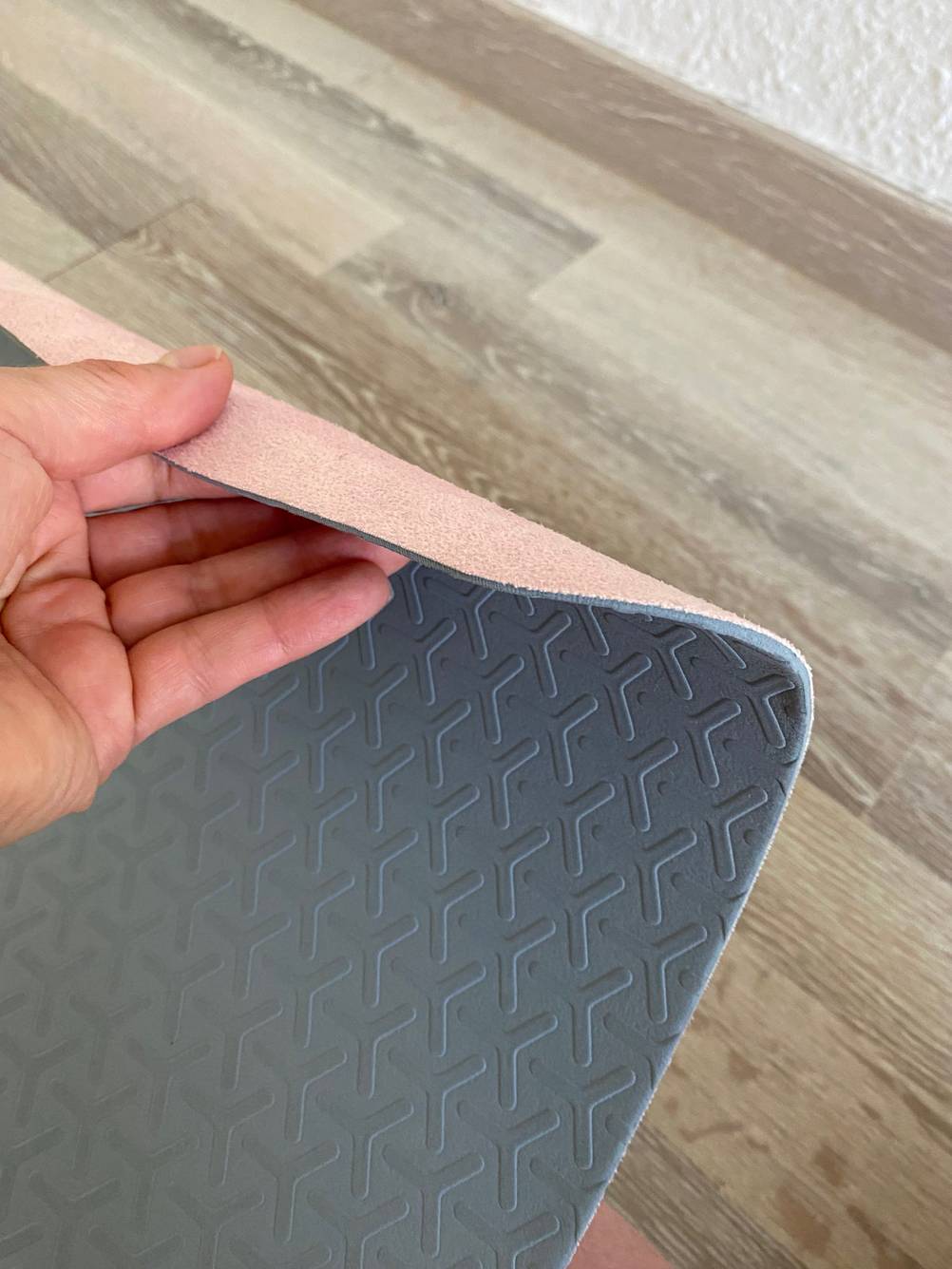 Yogamatte Naturkautschuk im Test: Hand dreht eine Yogamatte um und zeigt das Material der Ober- und Unterseite.