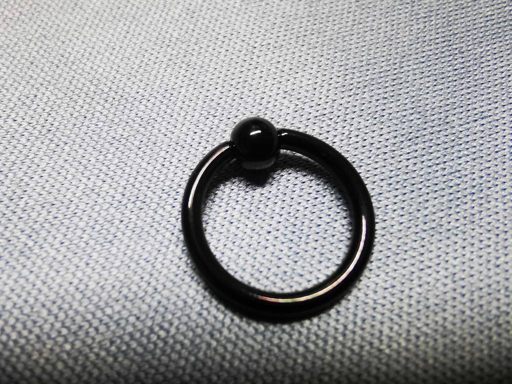 Ein Piercing in Ringform liegt getestet auf einer hellen Fläche.