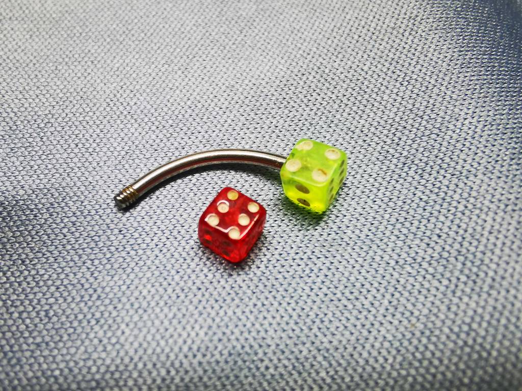 Im Test: Ein Piercing im Würfeldesign liegt auf einer hellen Fläche.