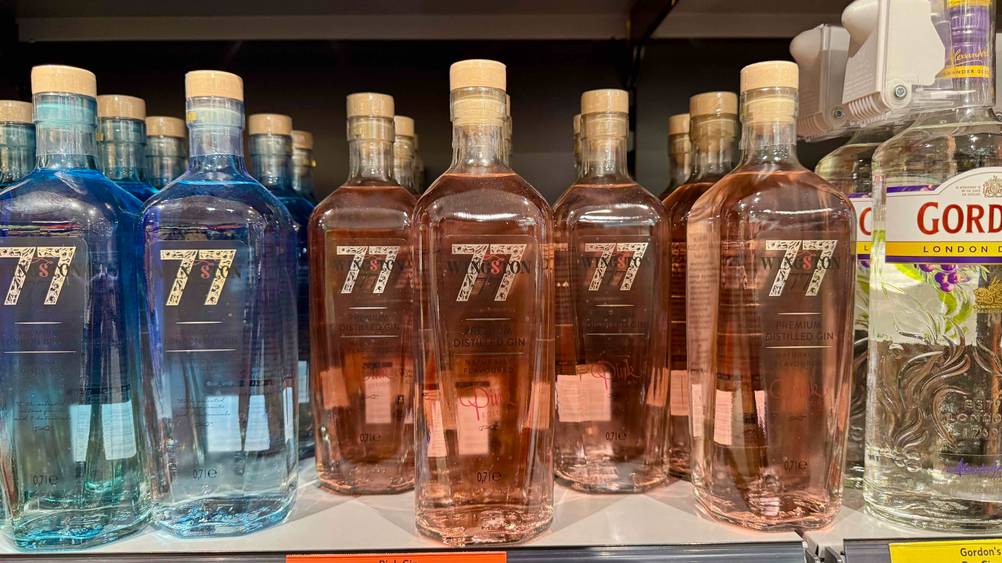 Mehrere Flaschen des Pink Gin im Test stehen in einem Verkaufsregal neben anderen Produkten.