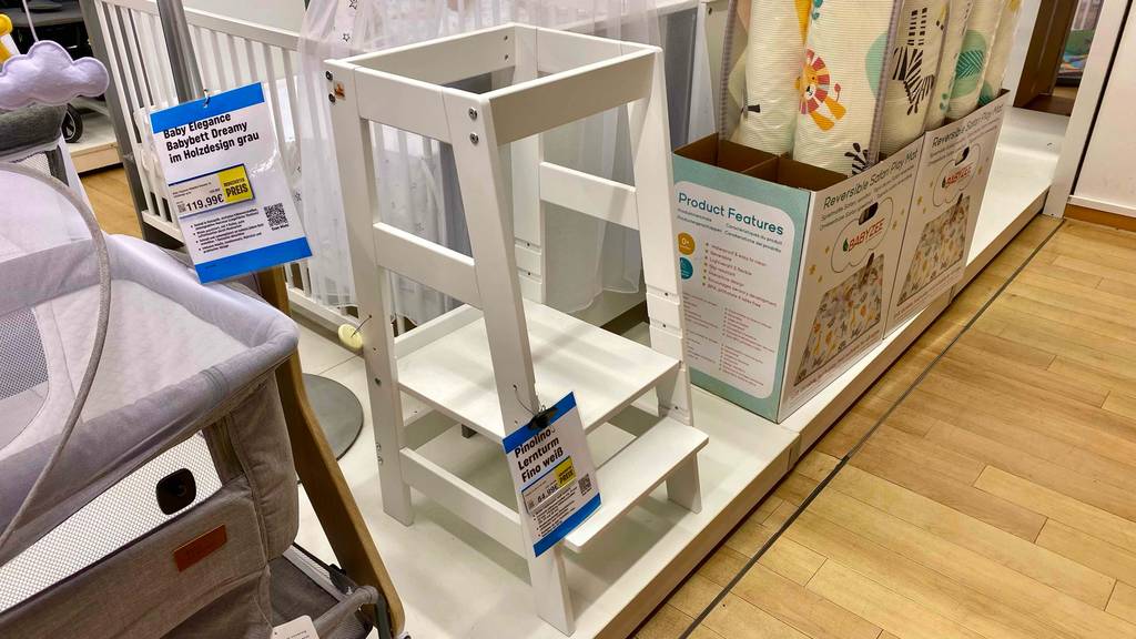 Getestet: Ein Lernturm in Weiß steht zwischen weiteren Kindermöbeln in einem Verkaufsbereich.