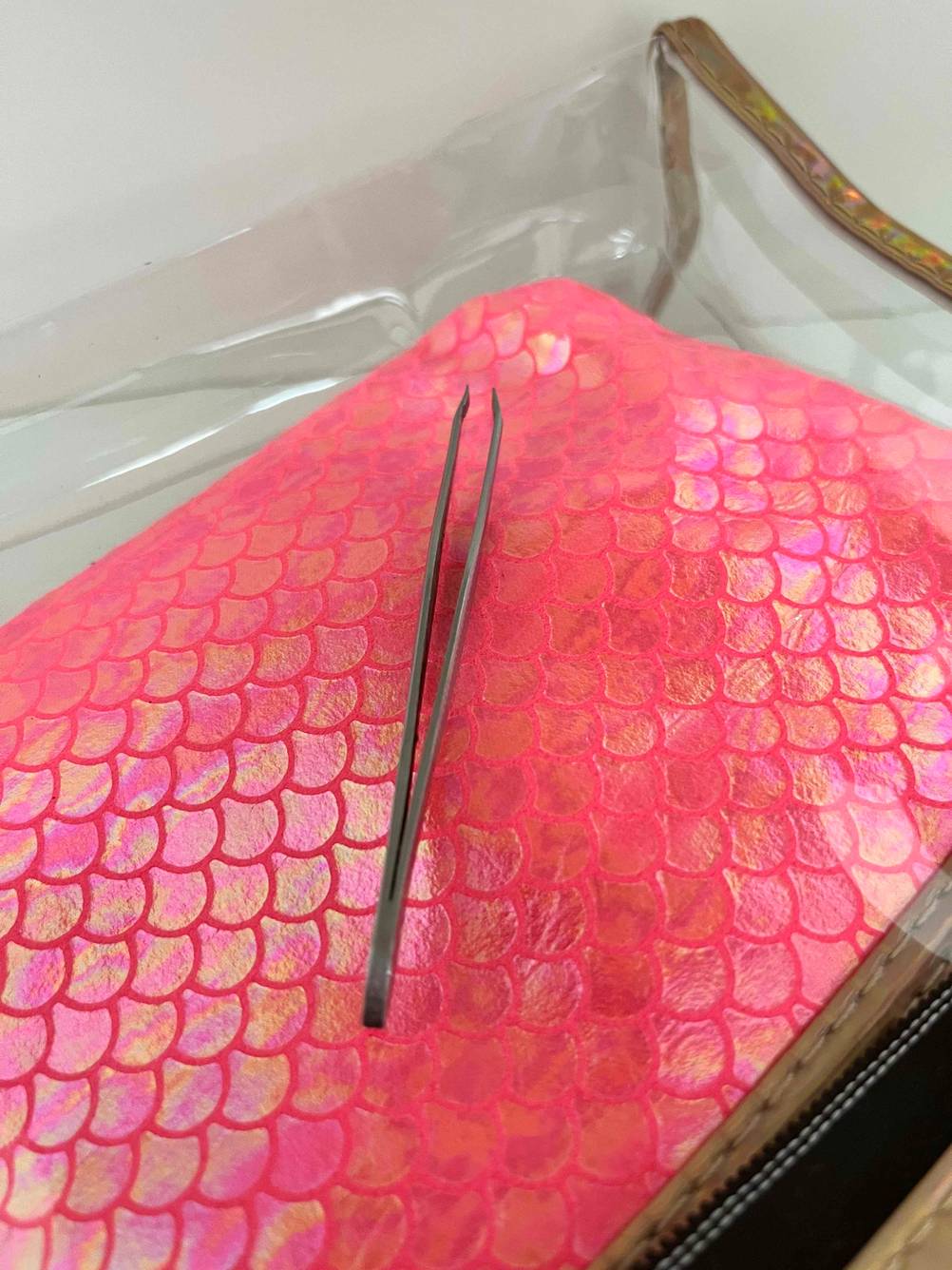 Im Test: silberne Pinzette liegt auf rotem Kosmetiktäschchen.