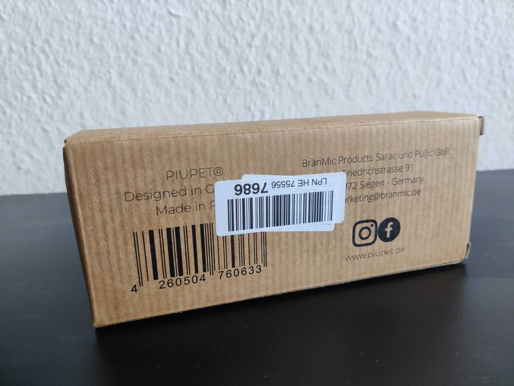 Die Rückseite der Originalverpackung einer getesteten Katzenbürste auf einer dunklen Fläche.