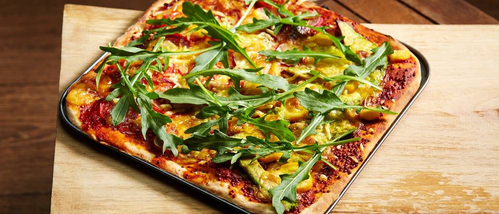 Selbstgebackene Pizza auf einem rechteckigen Pizzablech.