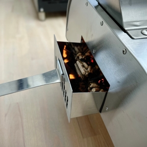 Der Pelletbehälter des Big Horn Outdoors SRPG18003 ist geöffnet. Glühende Pellets und erste Flammen sind sichtbar.