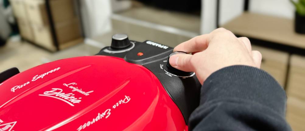 Jemand stellt die Temperatur am G3Ferrari Pizzaofen mithilfe eines Drehreglers um.