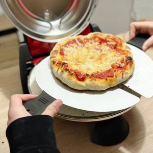 Eine fertige Pizza wird aus dem G3Ferrari Pizzaofen entnommen.