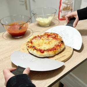 Eine fertige Pizza wird auf einem Holzbrett serviert.