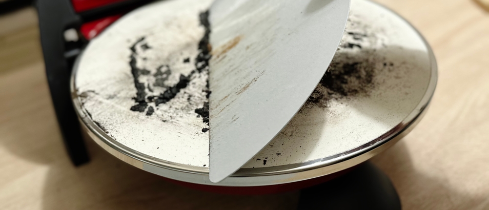 Mithilfe eines Schabers werden die Reste einer Pizza vom G3Ferrari Pizzaofen abgekratzt.