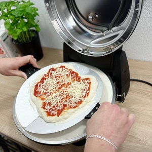 Eine belegte Pizza liegt auf dem Pizzastein im heißen G3Ferrari-G1003210-Pizzaofen. Die Oberhitze ist aktiv.