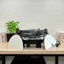 Der G3Ferrari G1003210 Pizzaofen mit geschlossenem Deckel steht auf einem Tisch. Zwei Pizzaschaufeln sind seitlich platziert.