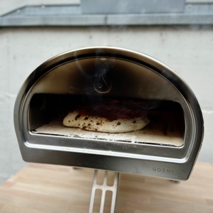 Eine Pizza mit dunklem Belag backt im Gozney Pizzaofen. Der Pizzaboden ist bereits stark gebräunt.