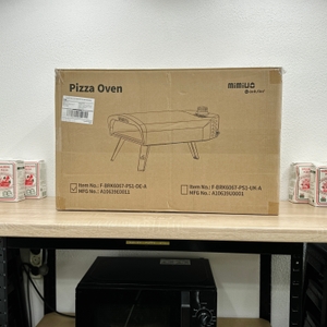 Die Originalverpackung des Mimiuo-Pizzaofens steht auf einem Tisch, das Markenlogo ist deutlich sichtbar.