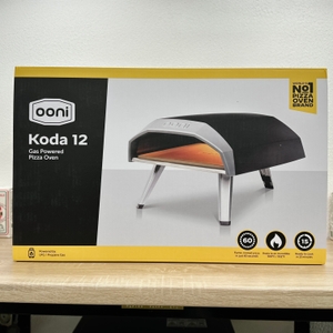 Die Vorderseite der Ooni Koda 12 Produktverpackung zeigt ein Produktfoto und Key-Features wie Temperatur, Dauer und Gasbetrieb.