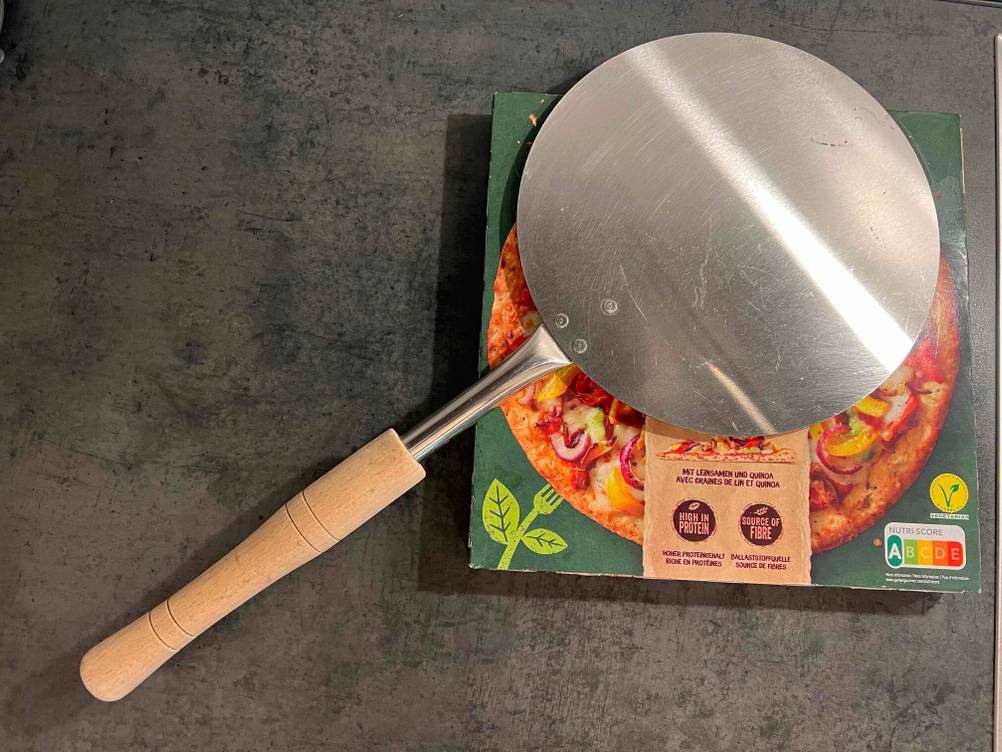 Auf einem Pizzakarton liegt eine getestete Pizzaschaufel.
