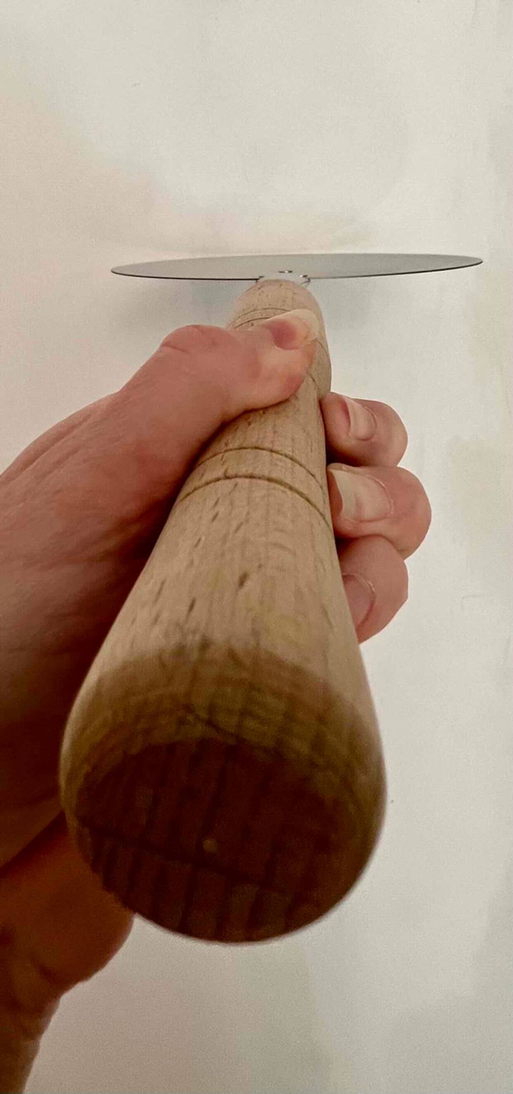 Nahaufnahme des Griffes einer Pizzaschaufel im Test von unten von einer Hand gehalten.