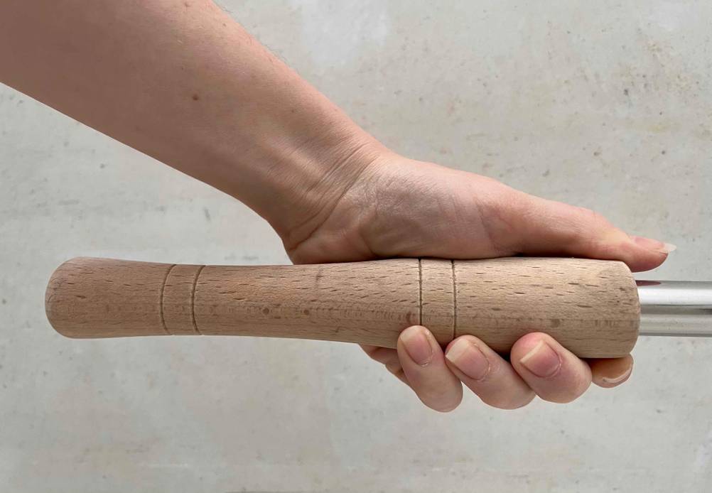 Nahaufnahme des Griffes einer getesteten Pizzaschaufel die eine Hand nach oben hält.
