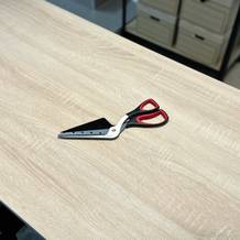 Die Pizzaschere von Asdirne liegt ausgepackt auf einem Holztisch.