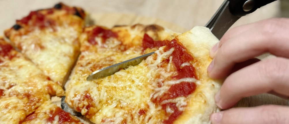 Mit der Pizzaschere von Dreamfarm wird eine Pizza geschnitten.