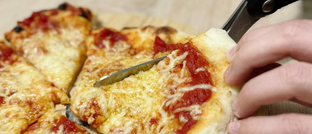 Mit der Pizzaschere von Dreamfarm wird eine Pizza geschnitten.