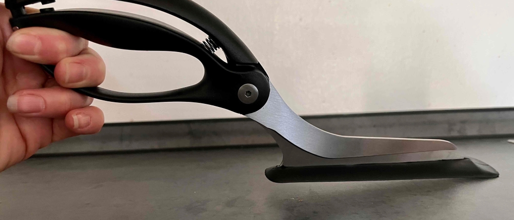 Getestet: Eine Pizzaschere von der Seite von einer Hand gehalten.