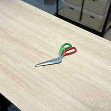 Die Pizzaschere von Triangle liegt ausgepackt auf einem Holztisch.