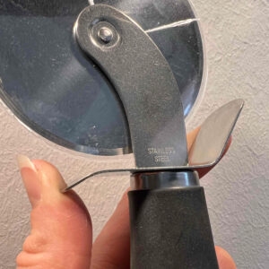 Nahaufnahme der Prägung 'Stainless Steel' eines getesteten Pizzaschneiders.