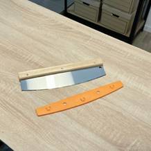 Der Pizzaschneider von Pizza Mondo liegt ausgepackt auf einem Holztisch.