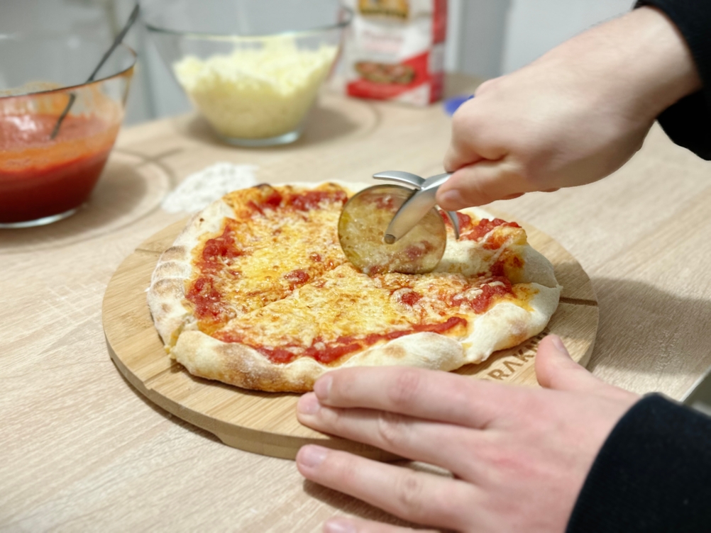 Eine Pizza wird mit dem Pizzaschneider von Valuxe geschnitten.