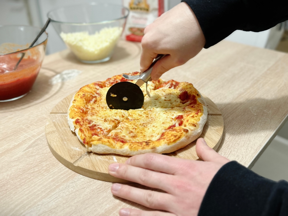 Eine Pizza wird mit dem Pizzaschneider von WMF geschnitten.