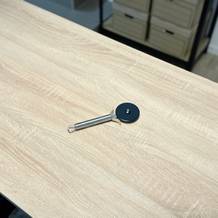 Der Pizzaschneider von WMF liegt ausgepackt auf einem Holztisch.