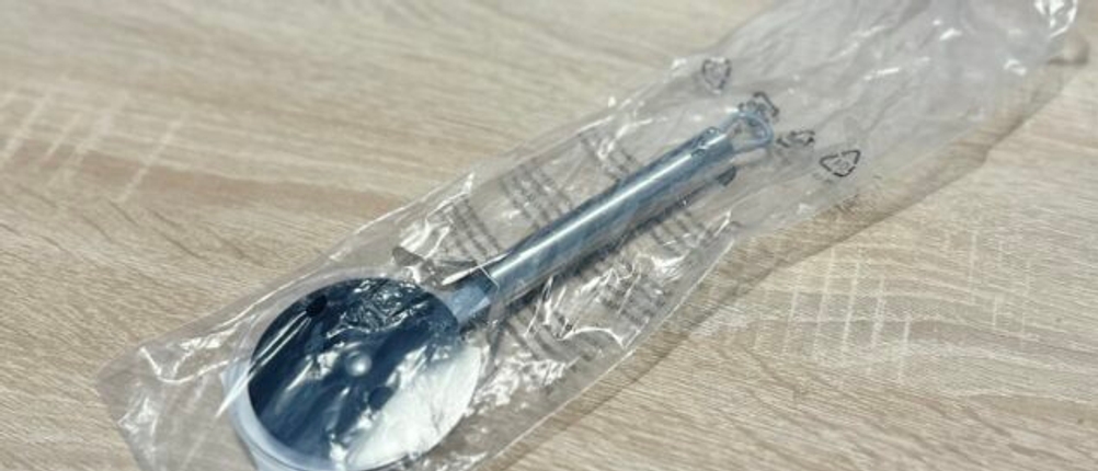 Der Pizzaschneider von WMF liegt eingepackt auf einem Holztisch.