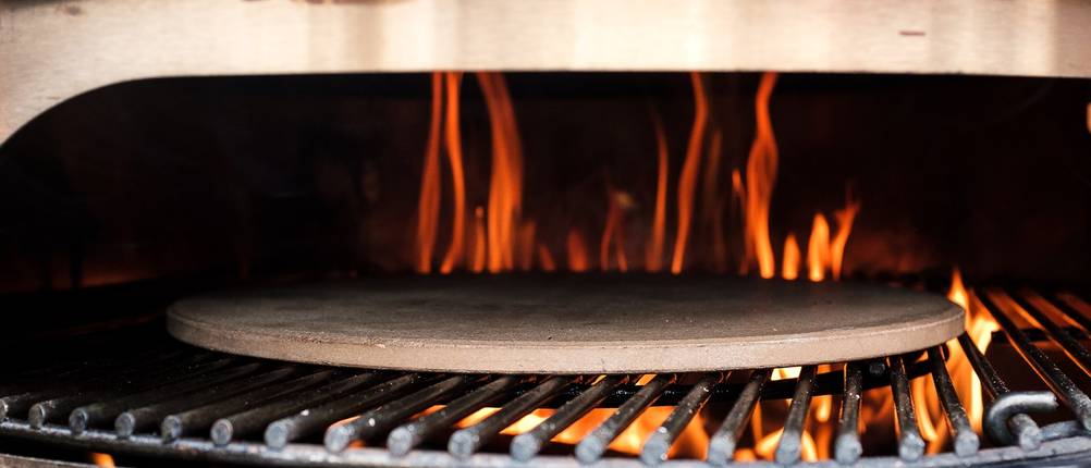 Pizzastein auf dem offenen Grill im Feuer.