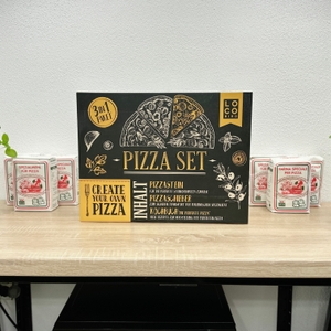 Die Vorderseite der Verpackung zeigt das Locbird Pizza Set mit Illustrationen und Angaben zum Lieferumfang. Der Karton steht mittig auf einem Tisch.