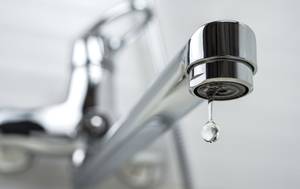 Wasserhahn mit einem einzelnen Tropfen in Nahaufnahme.