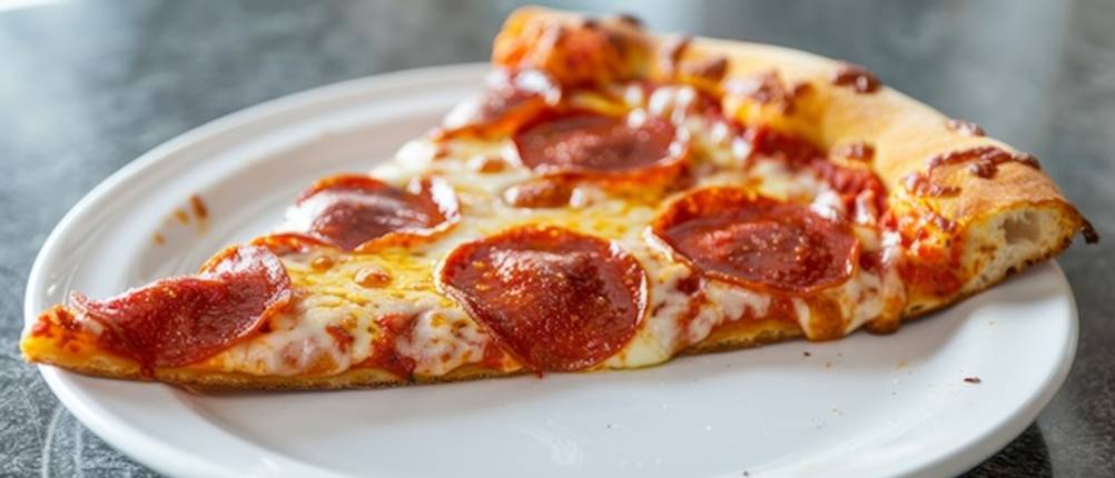 Pizzateller getestet: Nahaufnahme eines Salamipizza-Stücks auf einem zu kleinen Speiseteller.