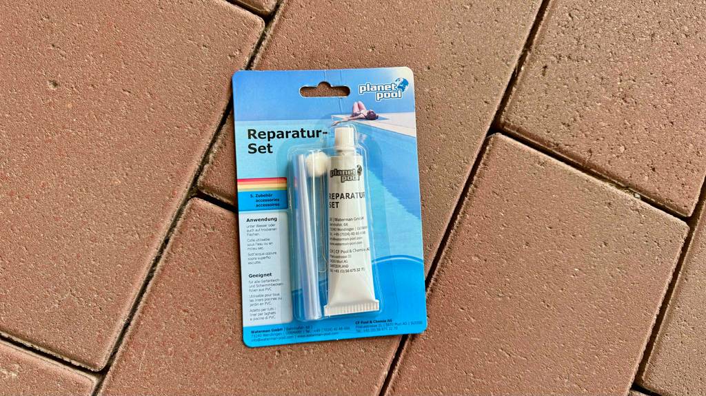 Eine Packung Pool-Reparaturset liegt zum Testen auf Pflastersteinen.
