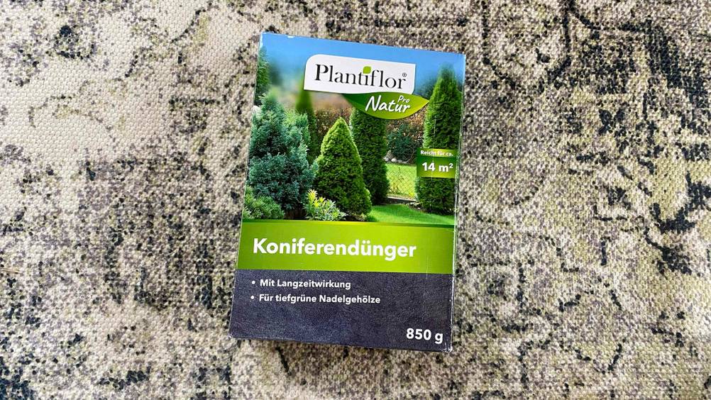 Eine Packung des getesteten Koniferendüngers auf einem beige-schwarzen Teppich.