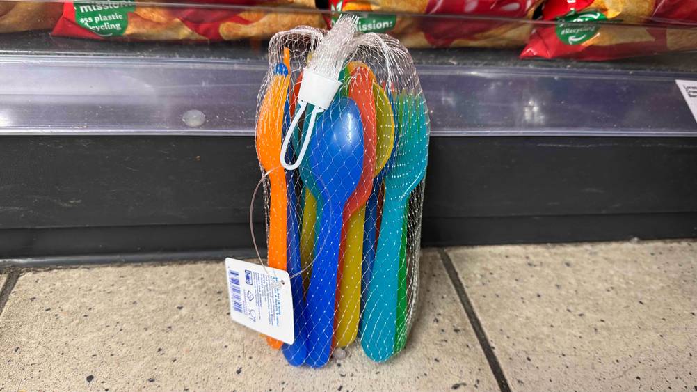 Eine Packung des getesteten Plastikbestecks vor einem Regal auf dem Boden.