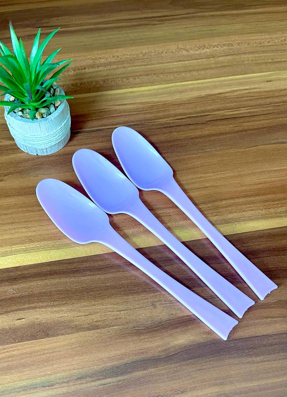 Getestet: Drei Plastiklöffel liegen vor einer Pflanze.