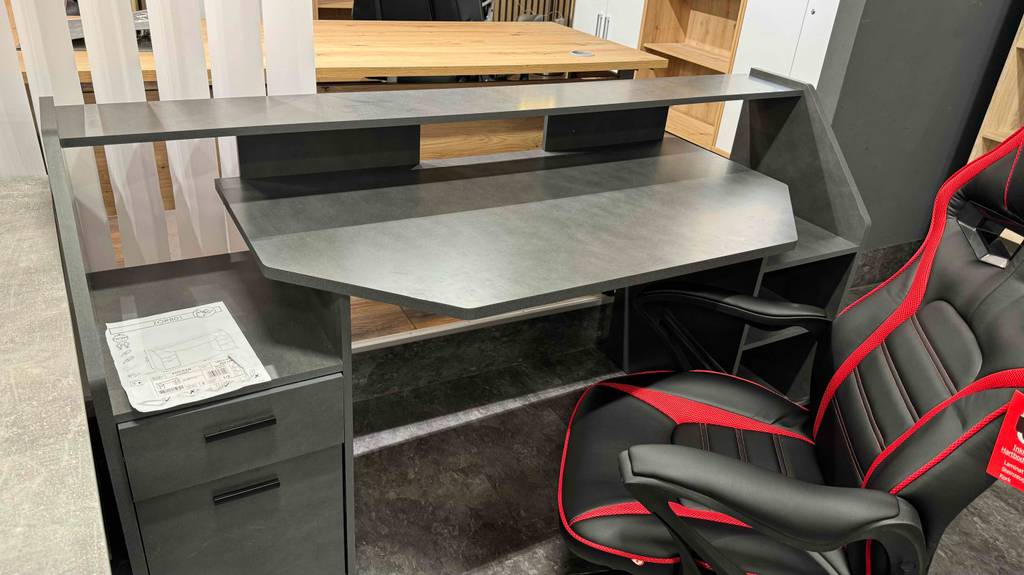 Im Test: Vor einem grauen Gaming-Tisch steht ein Gaming-Stuhl.