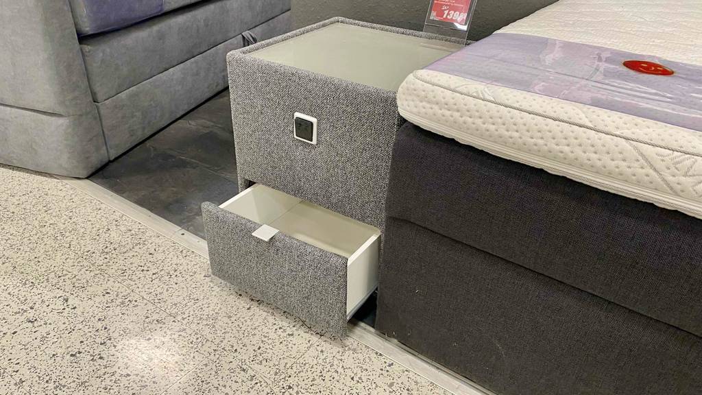 Im Test: Ein Nachttisch für Boxspringbett steht mit geöffneter Schublade neben dem Bett.
