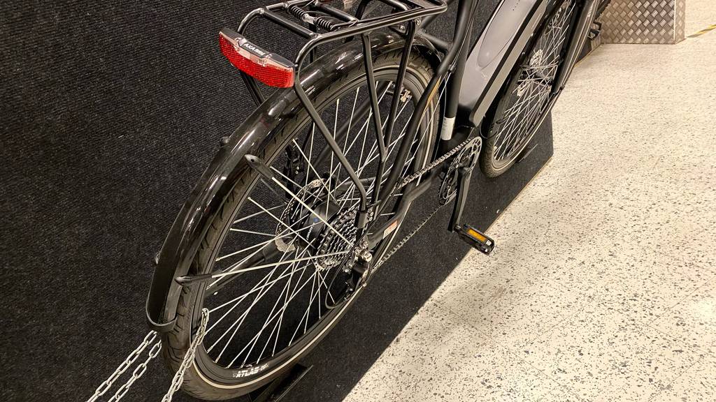 Trekking-E-Bike Herren: Ansicht von schräg hinten eines getesteten E-Trekkingbikes für Herren in einem Ausstellungsbereich.