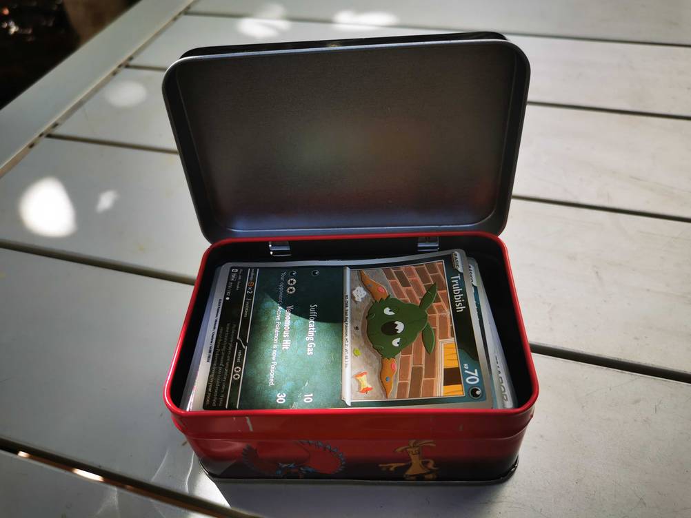 Eine geöffnete Pokémon-Box im Test auf einem grauen Tisch.