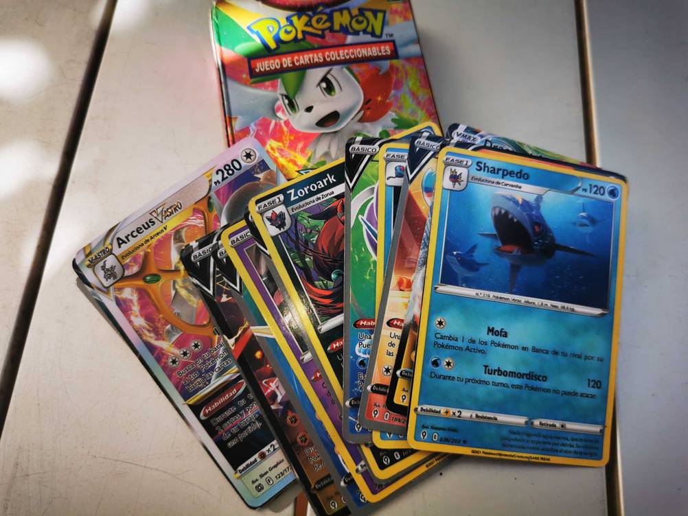 Mehrere Karten aus dem getesteten Pokémon-Deck übereinander liegend auf einer hellen Fläche.