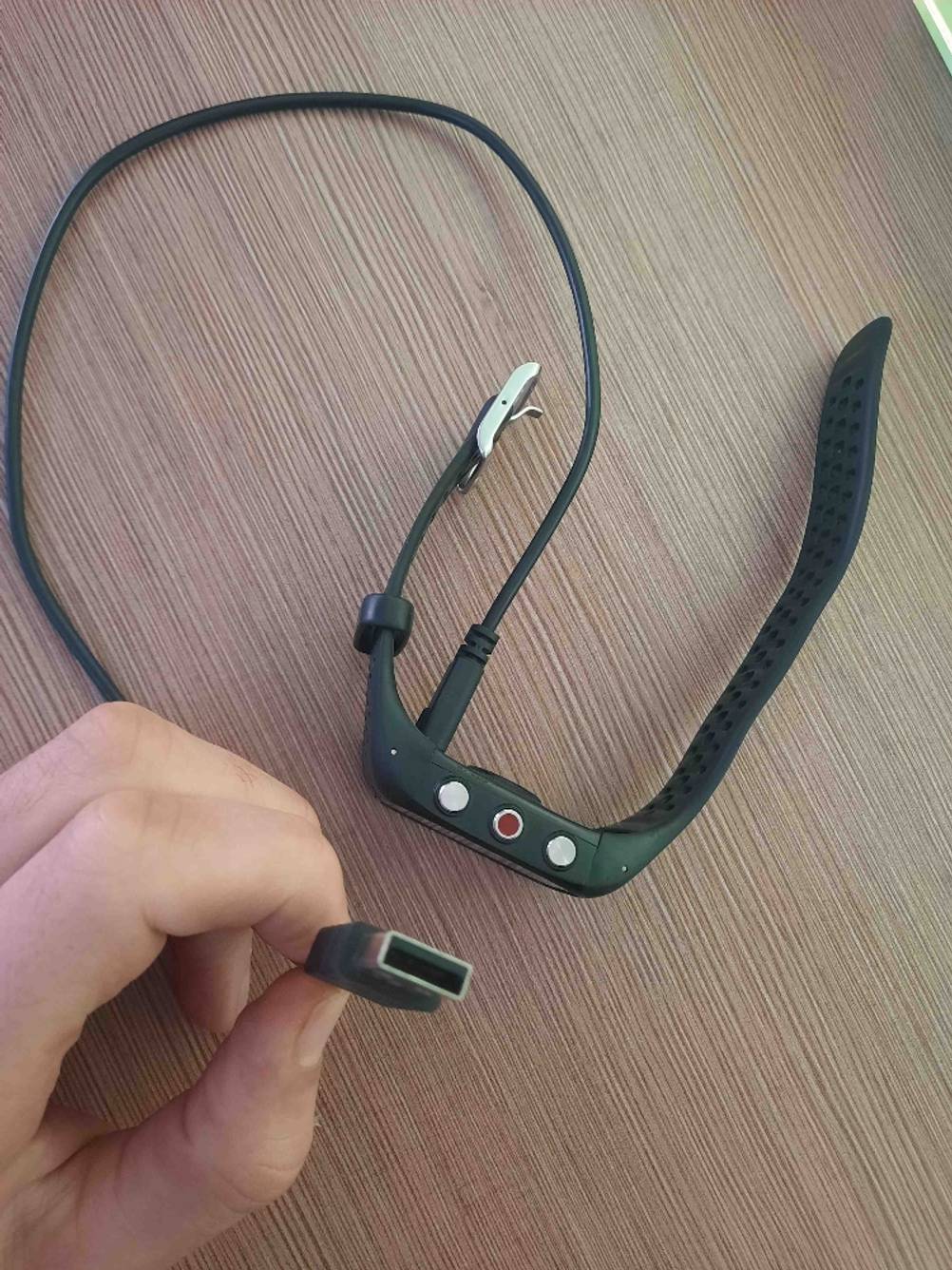 Eine Polar-Pulsuhr im Test auf der Seite liegend mit angeschlossenem Kabel, eine Hand hält das Ende des Kabels hoch.
