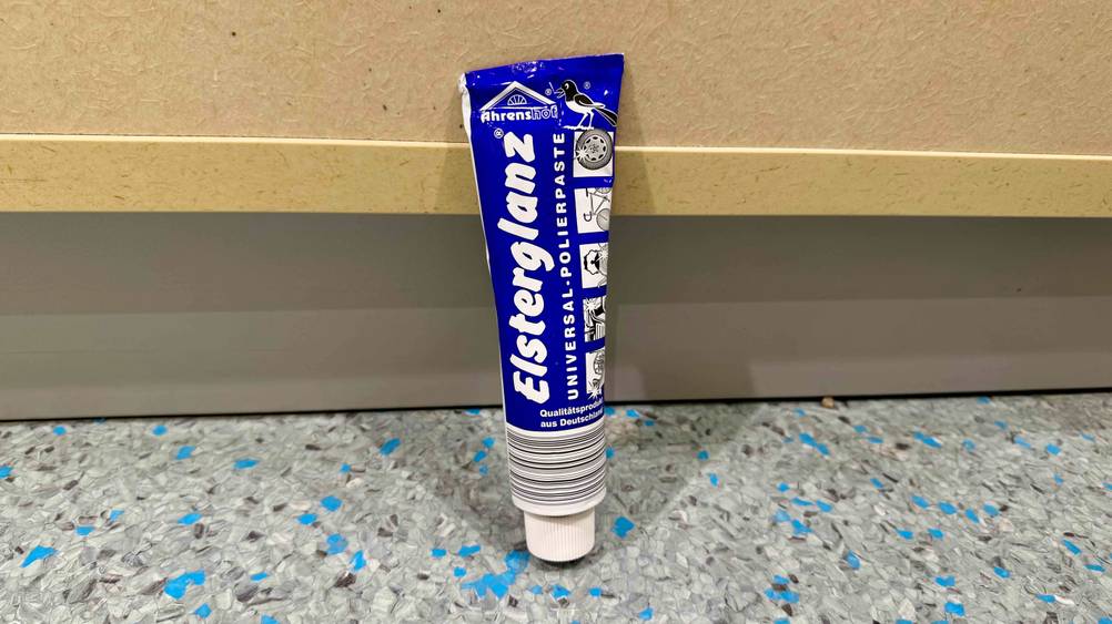 Die getestete Polierpaste lehnt an einem Schrank auf dem Boden.